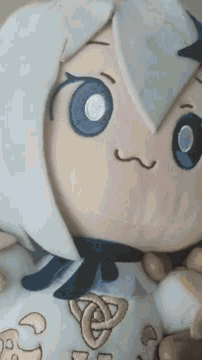 a person is holding a stuffed animal that looks like a cartoon character with blue eyes .