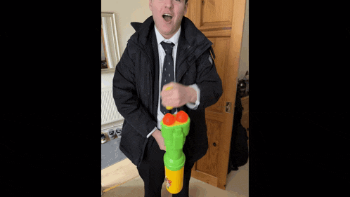 a man in a suit and tie is holding a large green toy