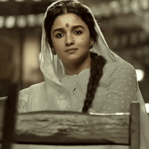 a woman with a veil on her head and a bindi on her forehead looks at the camera