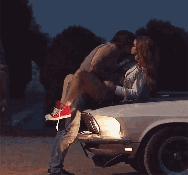 a man is carrying a woman on his lap in the back of a car .