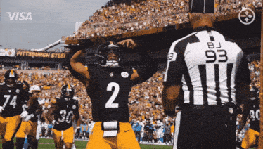 a football player with the number 2 on his jersey stands in front of a referee