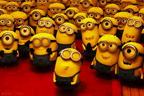 a group of minions are standing in a row on a red carpet .