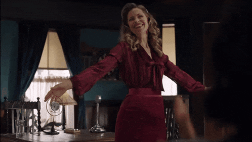 a woman in a red dress is standing in front of a desk