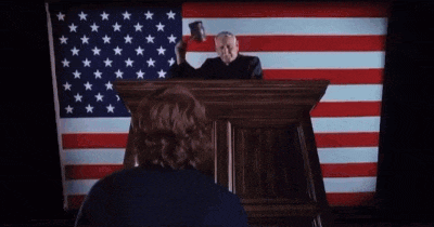 a man stands behind a podium with an american flag behind him