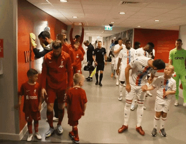 a group of soccer players are walking down a hallway with a sign that says cinch