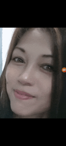 a close up of a woman 's face with an orange icon on the bottom right