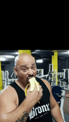 a man eating a banana in a gym wearing a bronx shirt