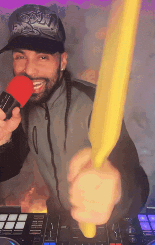 a man holding a microphone in front of a dj controller that says ' pioneer ' on the bottom