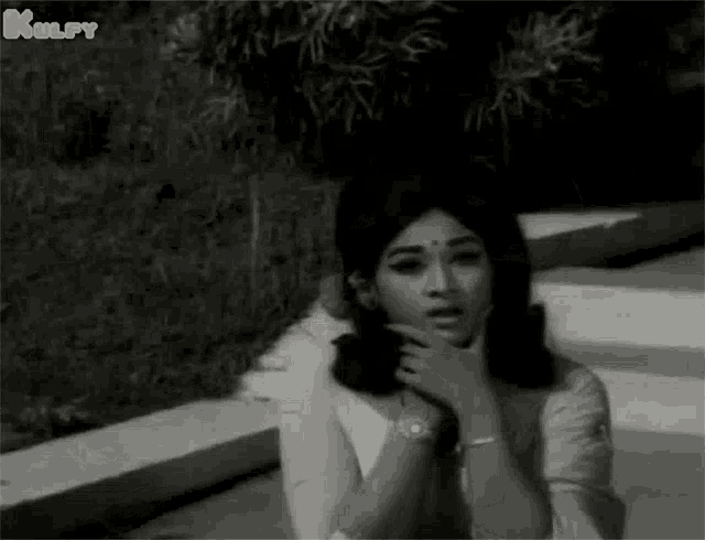 a black and white photo of a woman sitting on a set of stairs .