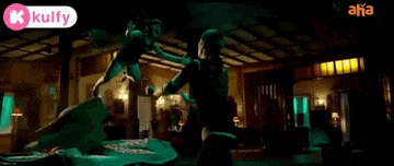 a woman in a green dress is dancing in a dark room with lights on .