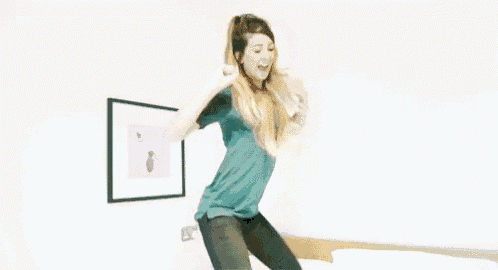 a woman is jumping on a bed in a room while holding her hair .