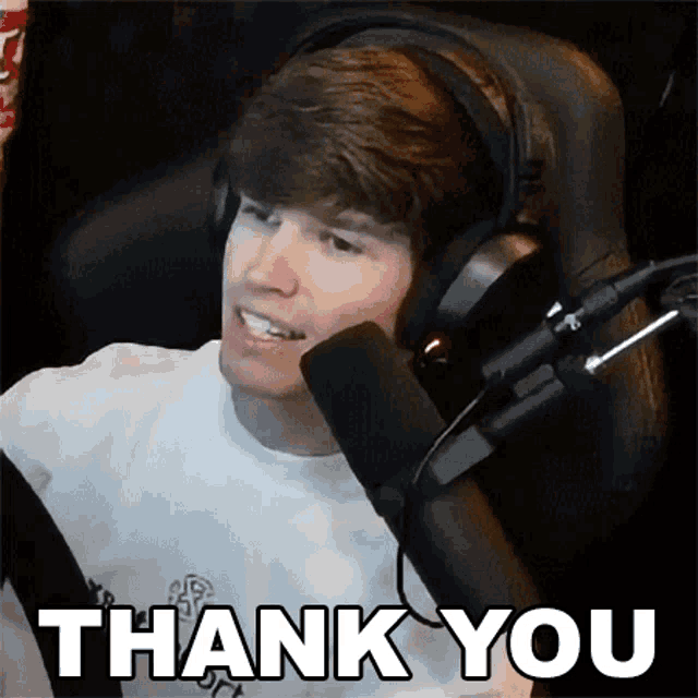 a young man wearing headphones is sitting in front of a microphone and saying thank you