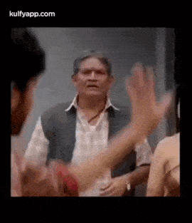 a man is talking to a woman while another man holds his hand up .
