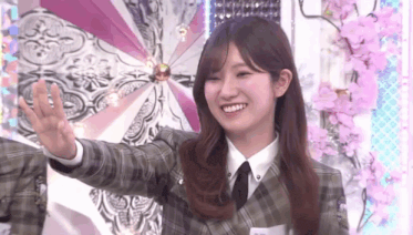 a woman in a plaid jacket and tie is holding a fan in her hand and smiling .