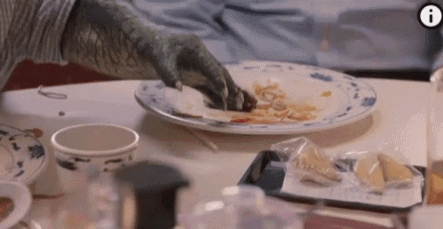 a dinosaur 's hand is reaching for a plate of food