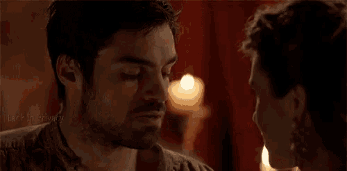 a man and a woman are kissing in front of a candle in a room .