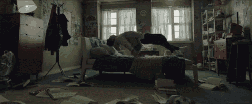 a person laying on their back on a bed in a messy bedroom