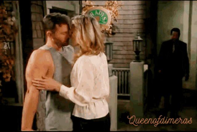 a man and woman are kissing in front of a sign that says ' radis '
