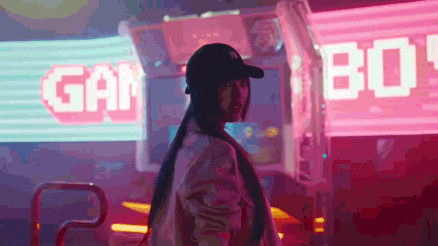 a woman in a baseball cap stands in front of a neon sign that says gan 80