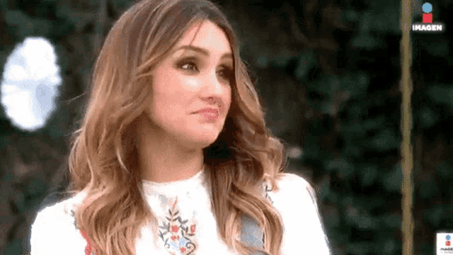 a woman with long wavy hair is making a funny face .
