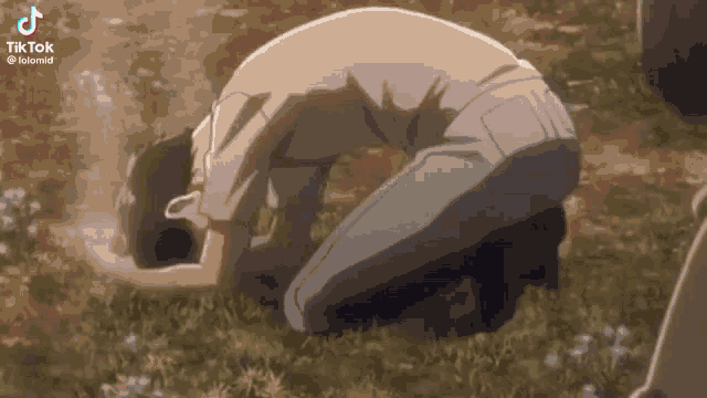 a man is kneeling down in the grass in a field .