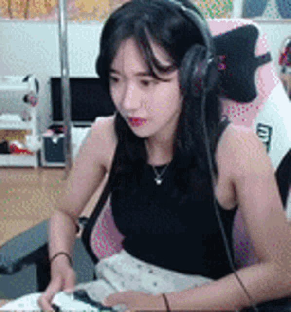 a woman wearing headphones and a black tank top is sitting in a chair .