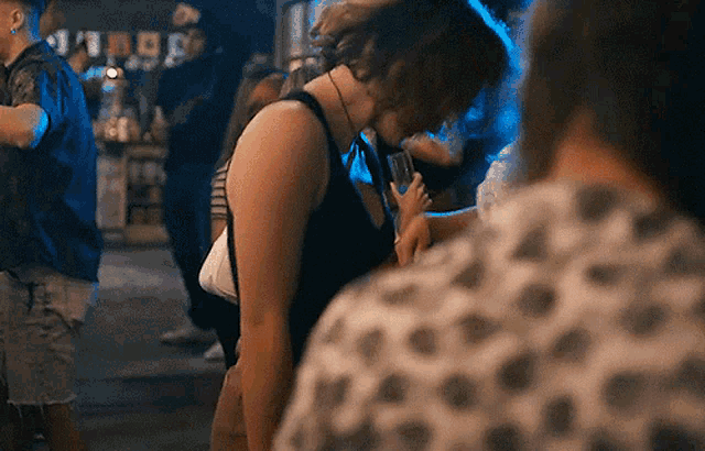 a woman in a black tank top is dancing in a crowded room