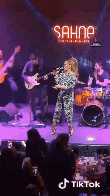 a woman singing on a stage in front of a sahne sign