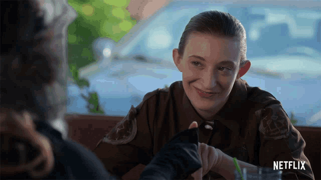 a woman in a sheriff 's uniform is sitting at a table with a netflix logo behind her