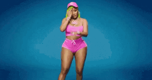a woman in a pink crop top and shorts is standing on a blue surface .