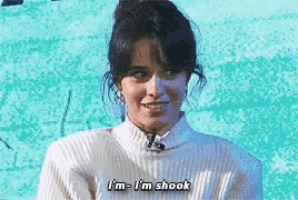 a woman is wearing a white sweater and says i 'm i 'm shook