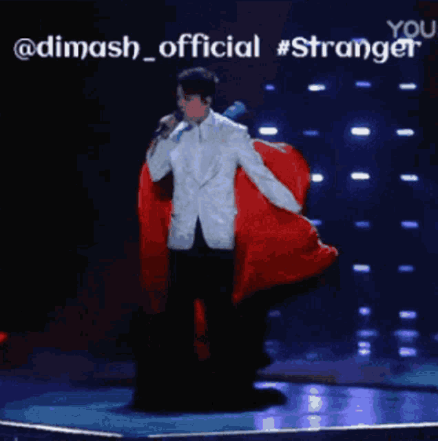 a man in a white suit is singing into a microphone while holding a red cloth
