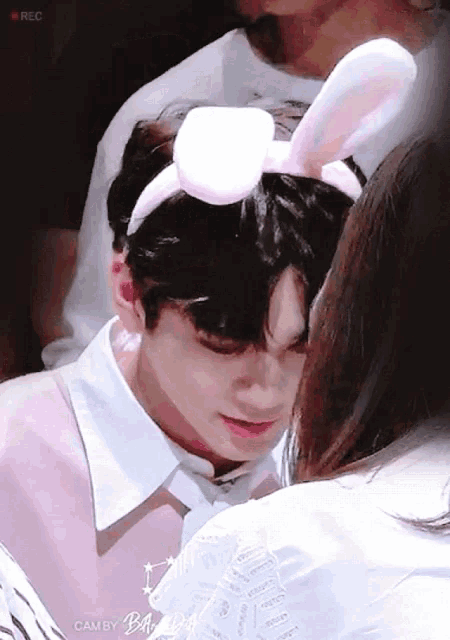 a boy wearing bunny ears is being kissed by a girl .