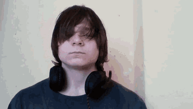 a young man wearing headphones against a wall