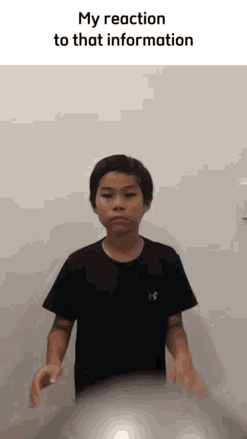 a young boy in a black shirt is holding a ball in front of a white wall with a caption that says my reaction to that information