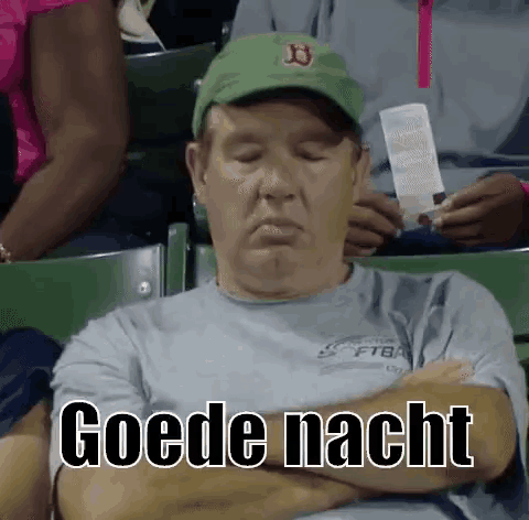 a man is sleeping in a stadium while wearing a green hat .