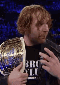 a man wearing a brooklyn shirt holds a championship belt around his shoulder