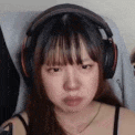 a close up of a woman wearing headphones and making a funny face .
