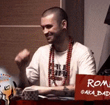 a man is sitting at a table with a red sign that says roma aka bad