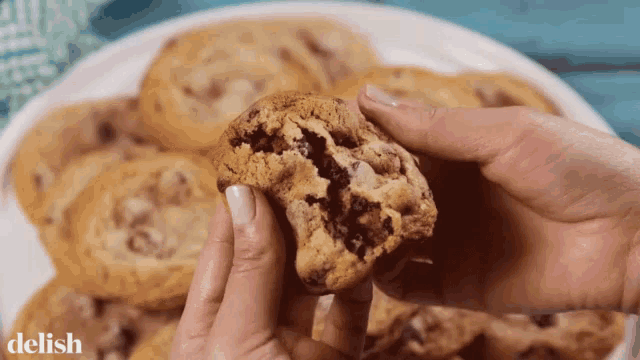 a person is holding a cookie with a bite taken out of it in front of a plate of cookies