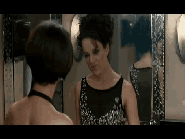 a woman is looking at her reflection in a mirror .