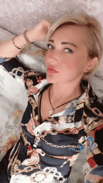 a woman wearing a shirt with a chain pattern is taking a selfie