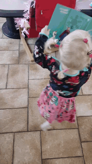a little girl in a pink dress is holding up a book that says ' a little princess ' on it
