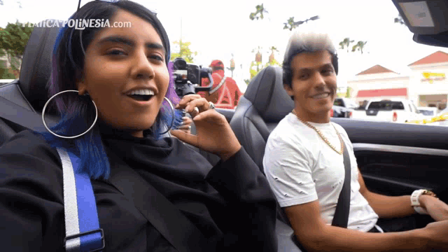 a woman with blue hair is sitting next to a man in a car and the website mexicopolinesia.com is visible