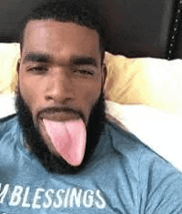 a man with a beard is sticking his tongue out while wearing a blue shirt .