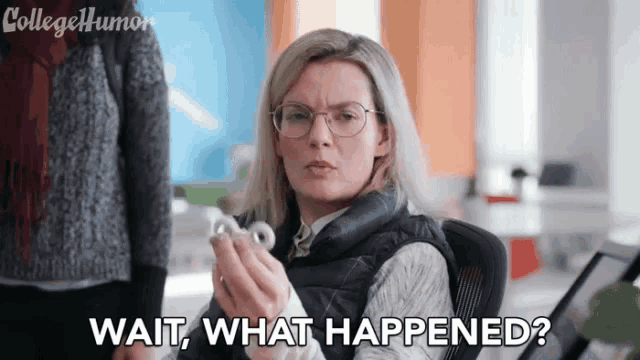 a woman wearing glasses is sitting in an office holding a small object .