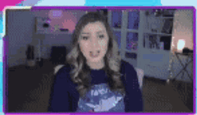a woman is sitting in front of a computer screen wearing a sweater .