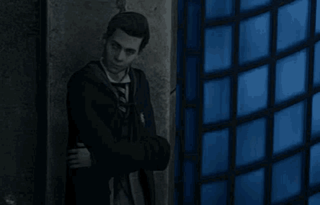 a man in a suit and tie is leaning against a wall in front of a blue window .
