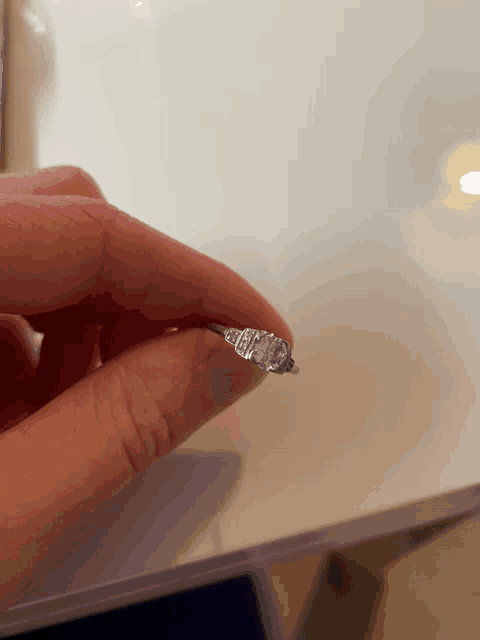 a person holding a diamond ring in their hand