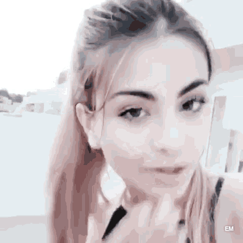 a close up of a woman 's face with a ponytail and a black tank top .